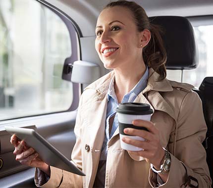 Mujer ejecutiva viajando en Taxi Premium